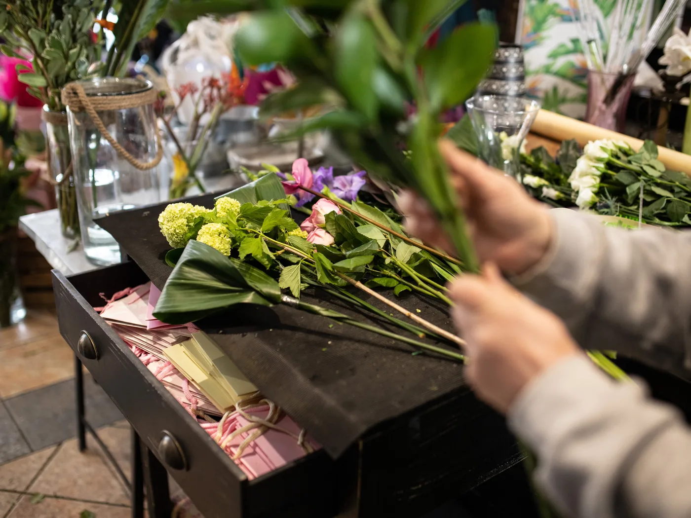 Une fleuriste assemble un bouquet sur son plan de travail